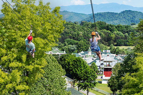 Two people zip down ziplines at Adventure Park Zip Lines in Sevierville, Tennessee, where guests staying at Xplorie participating properties can enjoy a free admission.