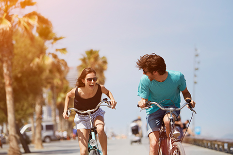 A young man and woman enjoying their bike rentals from Fat Tire Bikes in Tybee Island, Georgia, which is available for free to guests staying at Xplorie participating properties.