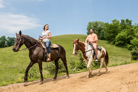A young couple enjoys a relaxing horseback ride from Five Oaks Riding Stables in Sevierville, Tennessee, which is available for free to guests staying at Xplorie participating properties.