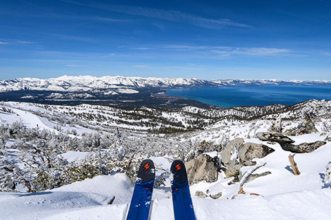 A skier overlooks the beautiful snow covered landscape of South Lake Tahoe, California, with a Performance Ski Package rental with Boots from Heavenly Sports Ski & Snowboard Rentals, which guests staying at Xplorie participating properties can enjoy for free.