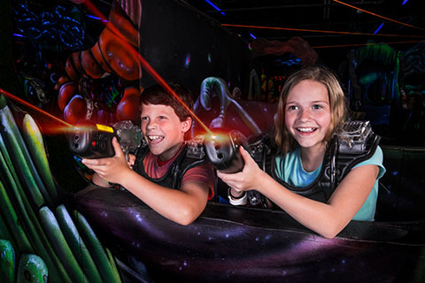 A young boy and girl enjoying an exciting game of laser tag at LazerPort Fun Center in Pigeon Forge, Tennessee, where guests staying at Xplorie participating properties can enjoy a free Park Hopper Pass.