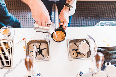 A barista pours a latte at Megaphone Coffee Company in Bend, Oregon, where guests staying at Xplorie participating properties can enjoy a free espresso or twelve-ounce drip coffee.