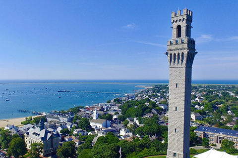 The Pilgrim Monument stands above the Provincetown Museum on a clear, sunny day in Provincetown, Massachusetts, where guests staying at Xplorie participating properties can enjoy a complimentary general admission.