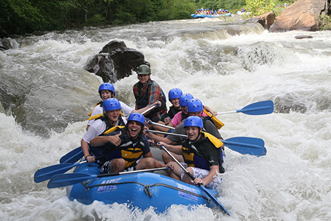 A group of people enjoying a thrilling whitewater rafting adventure with Raft One in Ducktown, Tennessee, where guests staying at Xplorie participating properties can enjoy a free Middle Ocoee Trip.