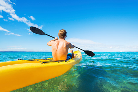 A man kayaking with a kayak rented from Reef Beach in Santa Rosa Beach, Florida, which is one of the many things guests can do for free when staying at an Xplorie participating property.