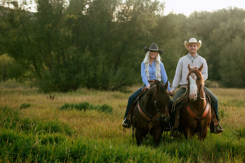 A couple riding horses pose for a photo in Midway, Utah. Guests staying at Xplorie participating properties can enjoy a free horseback ride including lesson from KB Horses.