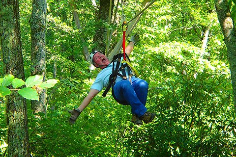 An excited man enjoys his Canopy Zip Tour from Sky Valley Zip Tours in Blowing Rock, North Carolina, where guests staying at Xplorie participating properties can enjoy a free admission.
