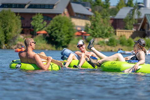 A group of friends enjoys a leisurely float down the water with a tube rental from Tumalo Creek Kayak & Canoe in Bend, Oregon, which guests can enjoy for free when staying at Xplorie participating property.