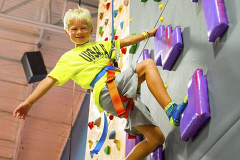 A boy scaling a wall at Urban Air Adventure Park in Destin, Florida, which is one of the many things guests can do for free when staying at an Xplorie participating property.