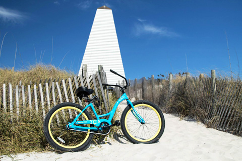 A bicycle rental from Vacayzen Rentals in Santa Rosa Beach, Florida, leans against a post on the sugar white sand beach, which guests can receive for free at Xplorie participating properties.