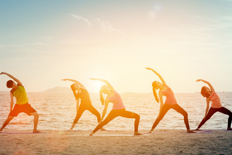 People enjoying yoga on the beach during sunset with Yoga Bohemia St. Augustine, which is available for free for guests staying at Xplorie participating properties.